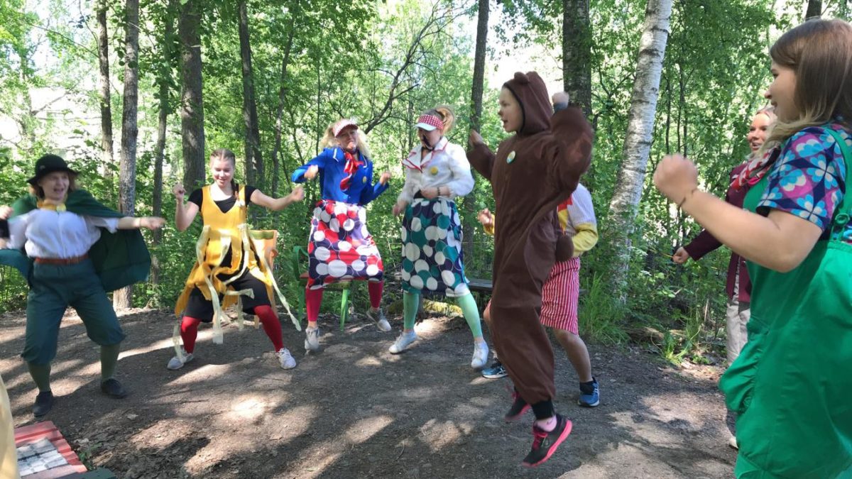 Valokuva, jossa kahdeksan värikkäisiin rooliasuihin pukeutunutta ihmistä tanssii ja hyppii.